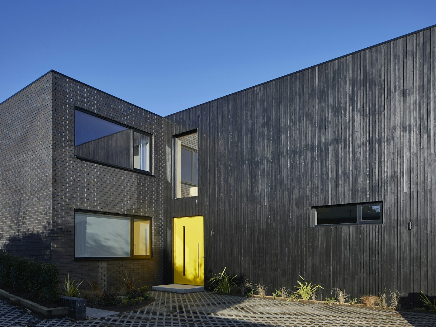 The door is an obvious choice to make a focal point. Colour is a really simple way to "wow" as this charred brick and black-clad house with bold yellow door highlights