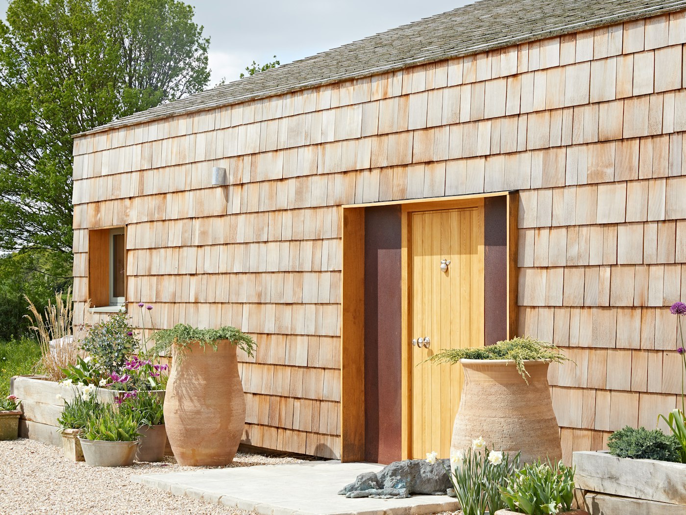 This Passivhaus build went all out on natural materials, combining cedar shingle cladding with a Passive oak front door and corten steel side panels. Oversized planters with a pop of greenery finish the look perfectly