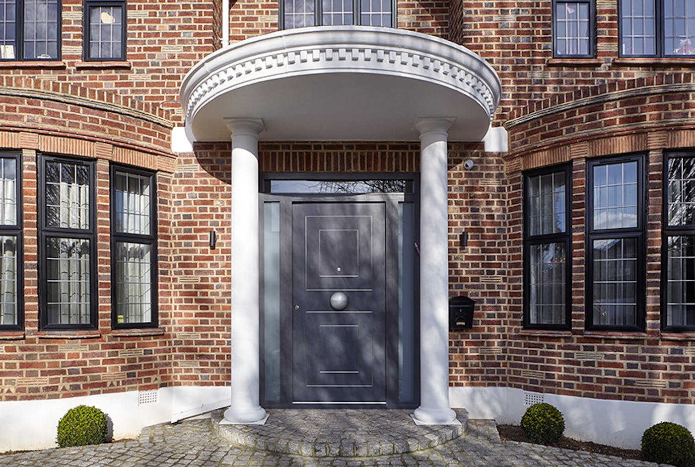 Black windows and a white portico porch make this dark grey door stand out