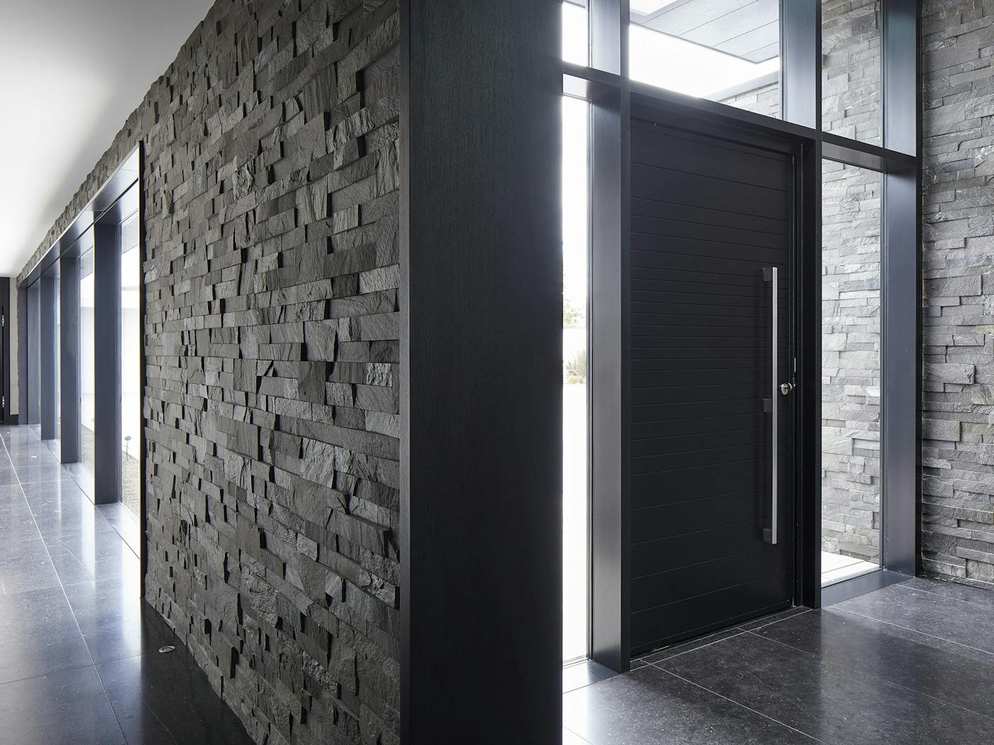 A modern classic, flanked by plenty of glass, this black door adds timeless elegance to the overall aesthetic of the house