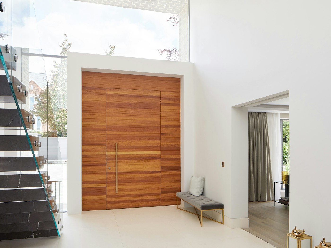 The matching side and overhead panels on the door create enormous impact, with warm iroko adding depth to the cool white walls