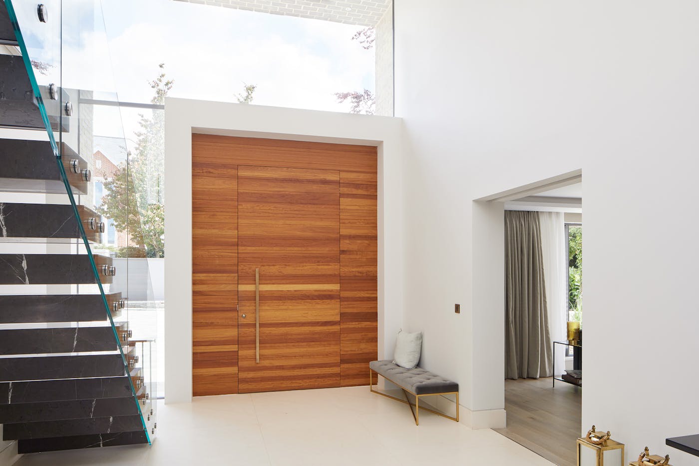 The matching side and overhead panels on the door create enormous impact, with warm iroko adding depth to the cool white walls