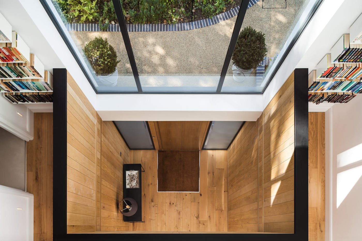 The first steps into the hall are framed by an overhead void, the glass letting all the light in 