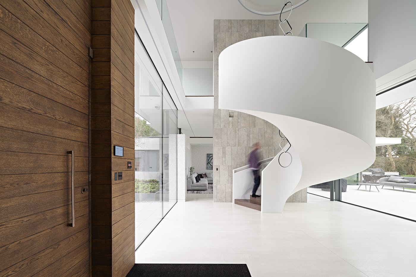 The walnut-stained door adds warmth to the light interior as you step into the hallway, where the spiral staircase takes pride of place