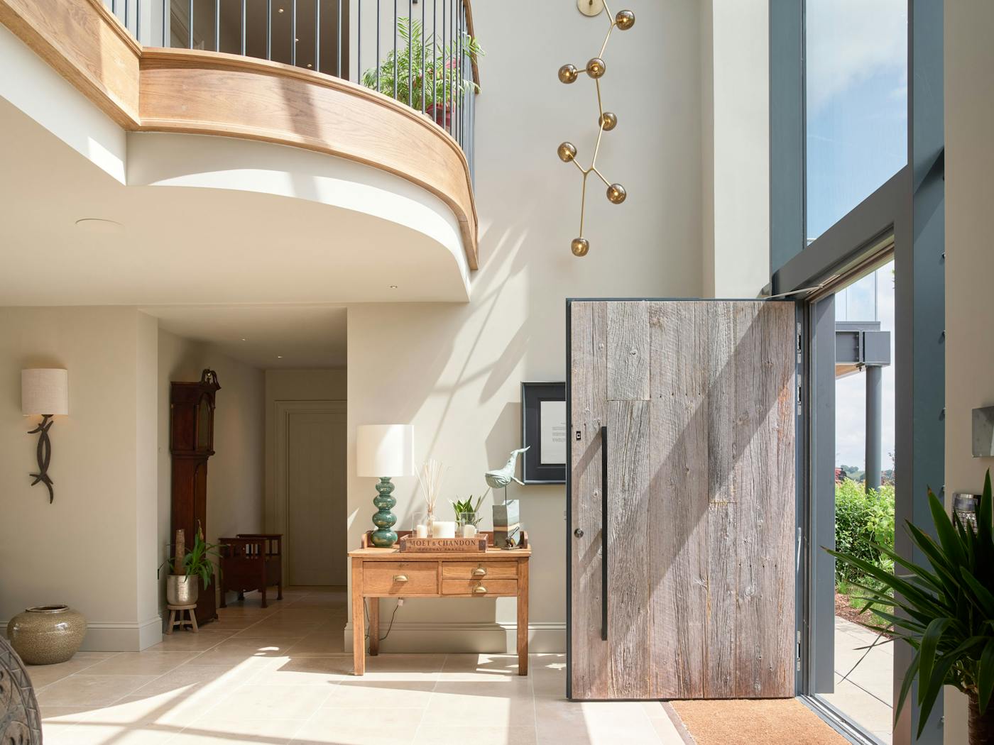 A galleried landing, cascading art, and an oversized Barn door make for an impressive welcome
