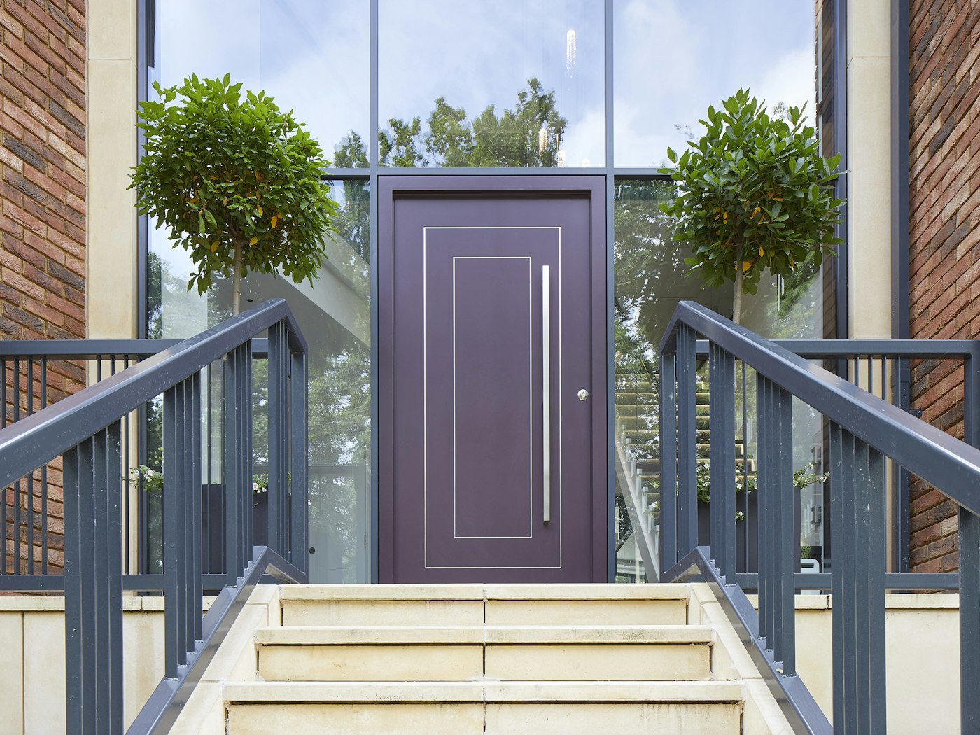 The black aluminium walling, red brick and beige tones of the exterior balance beautifully with the purple door