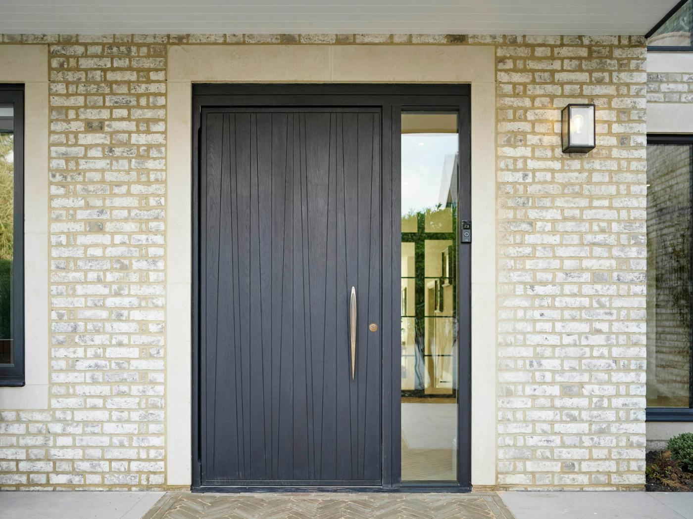 A single sidelight and light brick are the perfect surround for this black Milano V door 