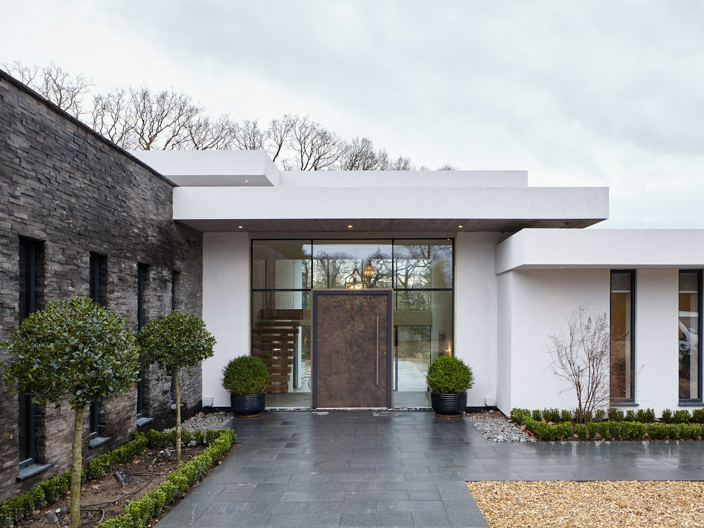 This luxury bronze door brings together the mix of white render, glass walling and grey stonework