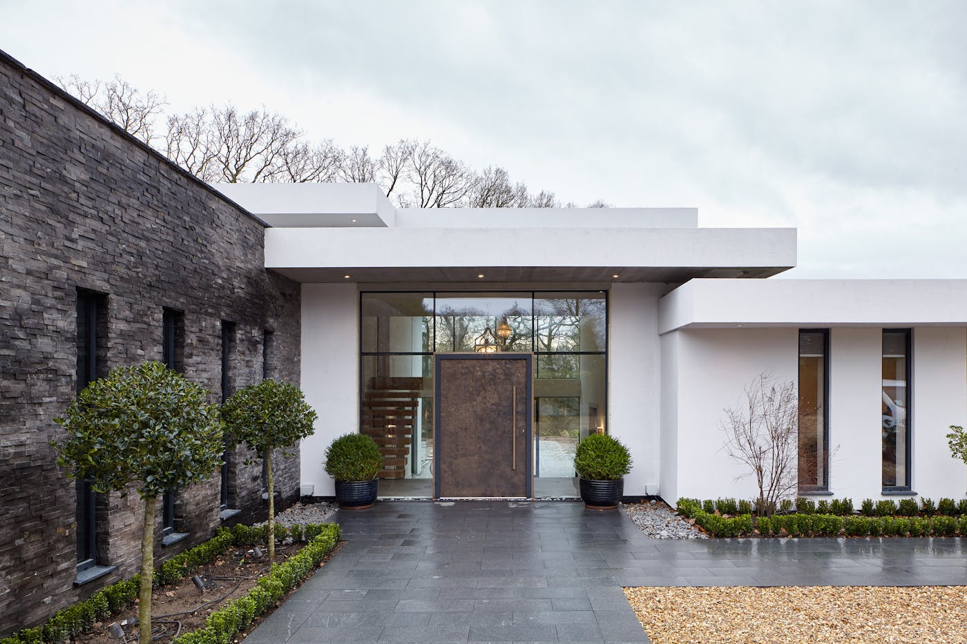 This luxury bronze door brings together the mix of white render, glass walling and grey stonework