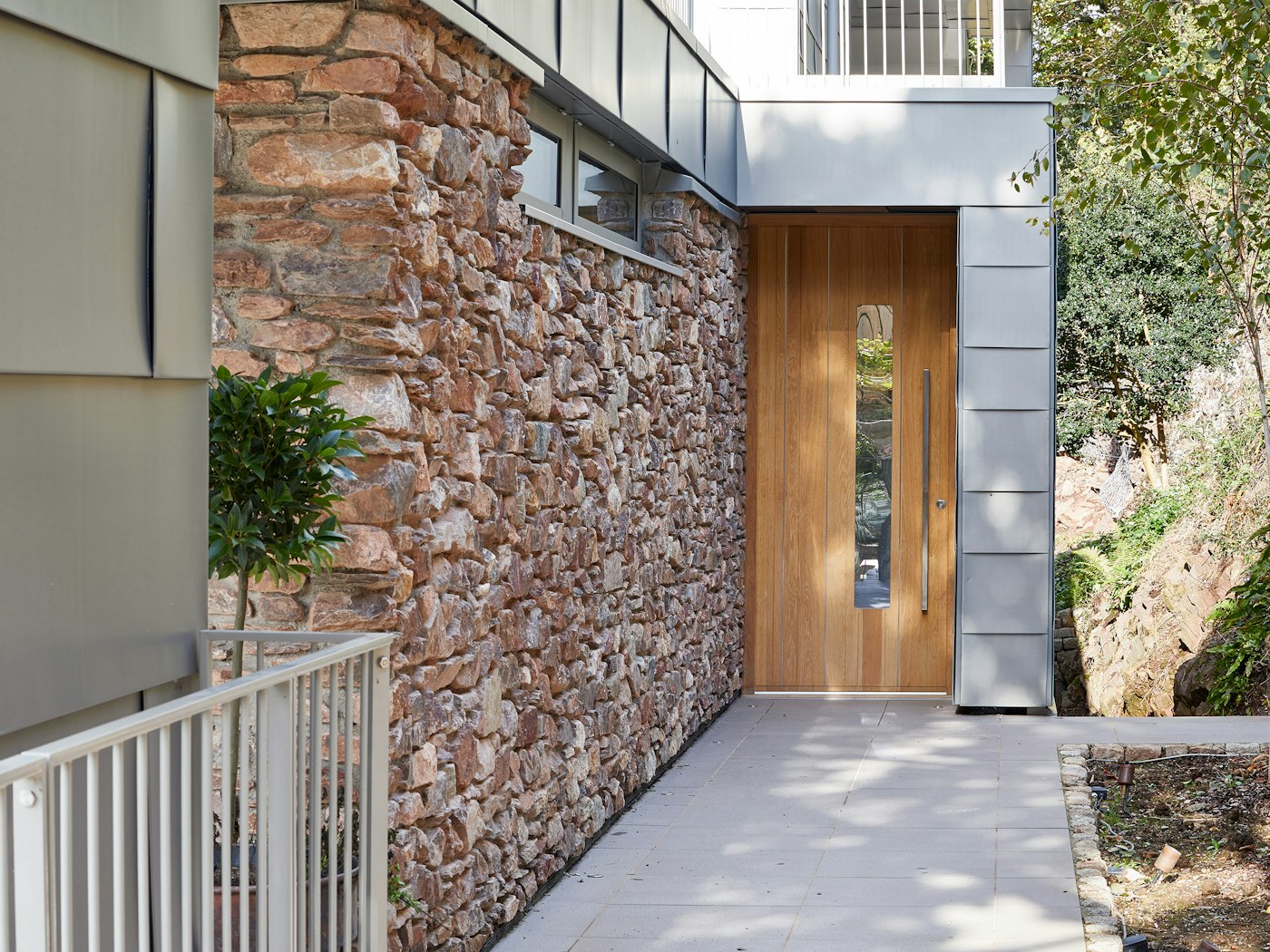 europen oak front door with grey cladding and stone wall
