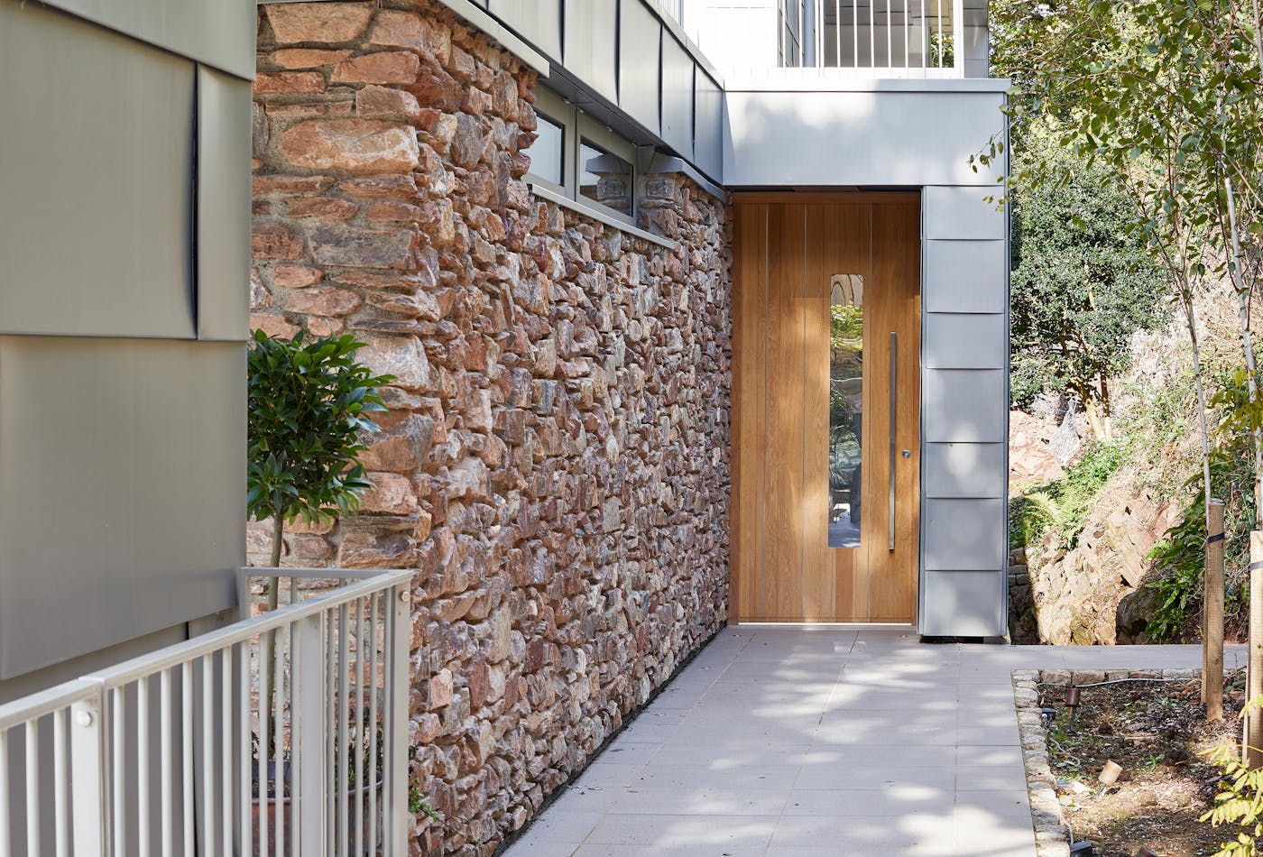 europen oak front door with grey cladding and stone wall