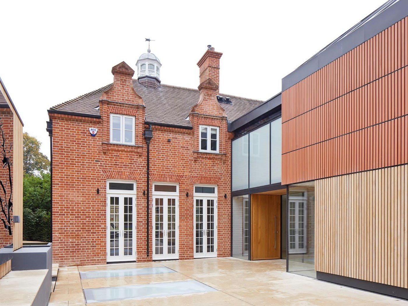 The warmth of the iroko front door works beautifully with the red brick and white windows of this house
