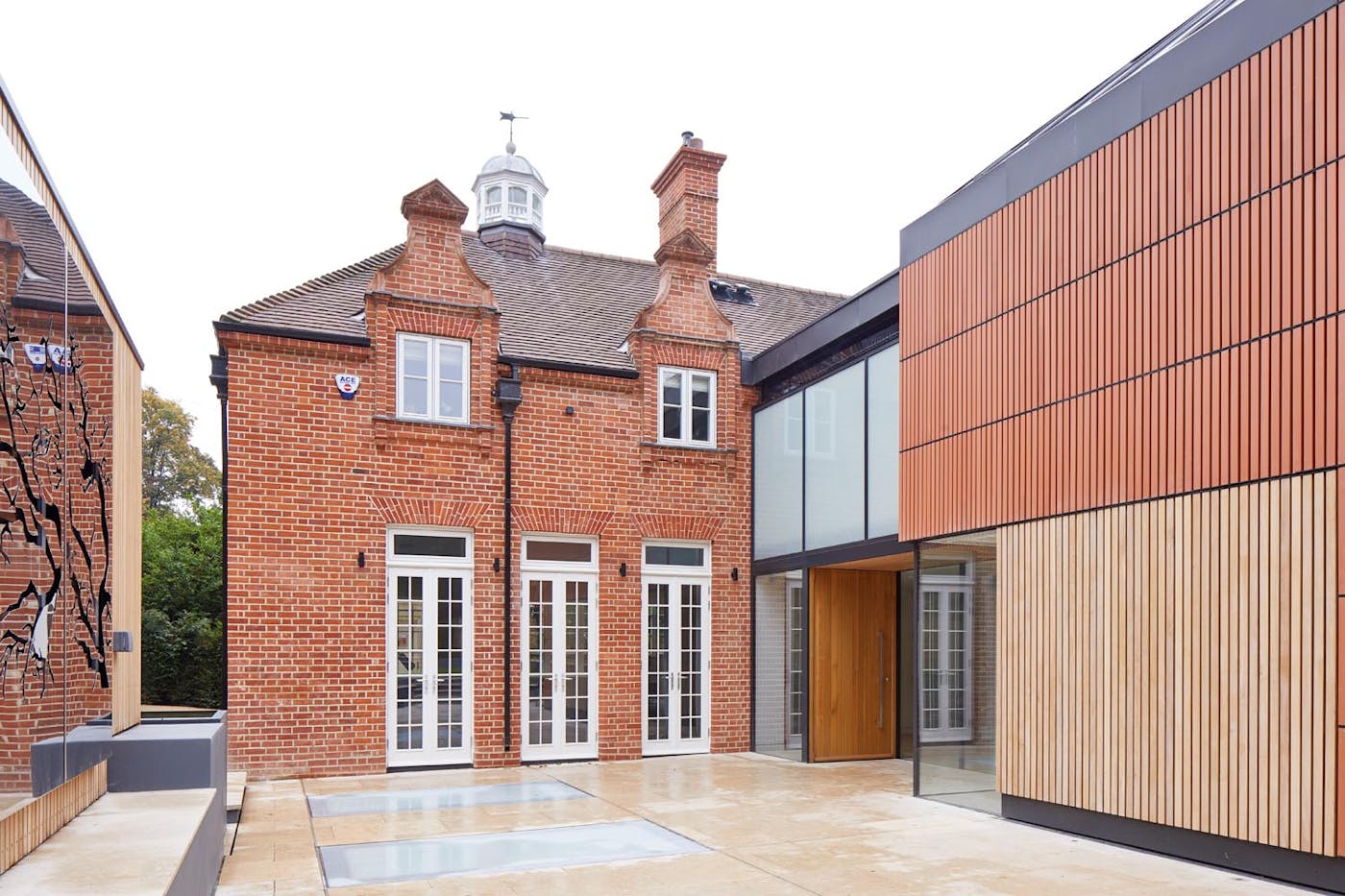 The warmth of the iroko front door works beautifully with the red brick and white windows of this house