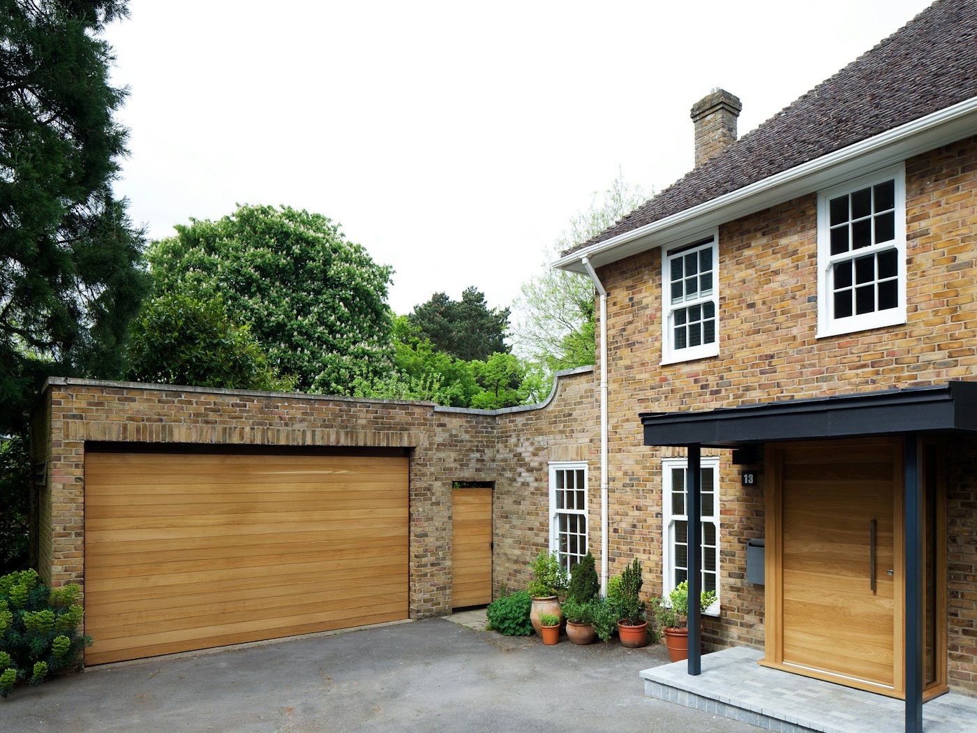 The light beige brick of this house is beautifully offset by matching front and garage doors in a warming european oak