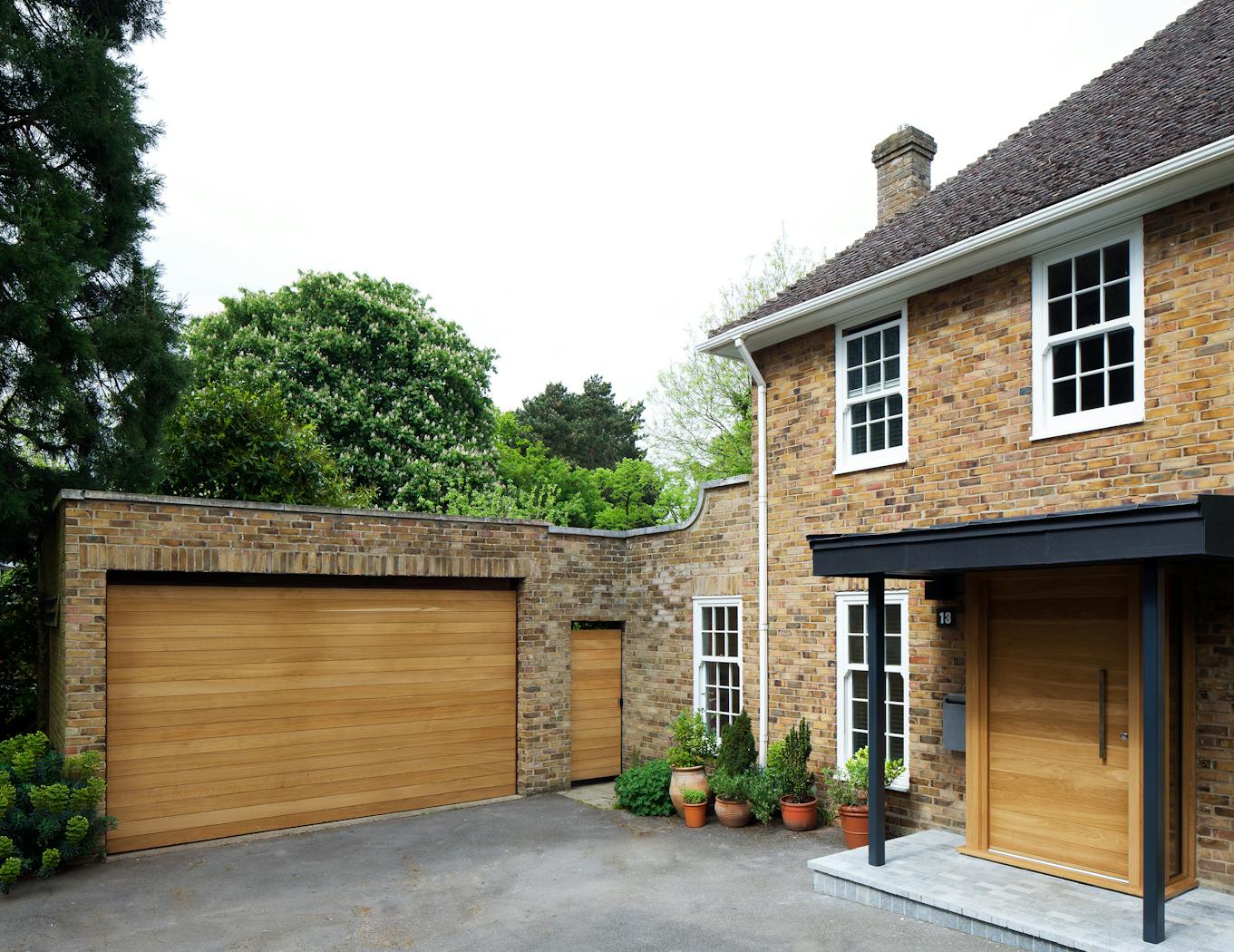 The light beige brick of this house is beautifully offset by matching front and garage doors in a warming european oak