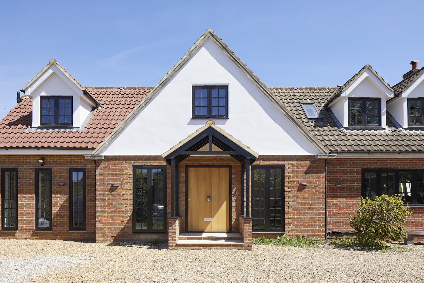 The black windows on this traditional house work perfectly with the lighter European oak front door and red brick of the facade 