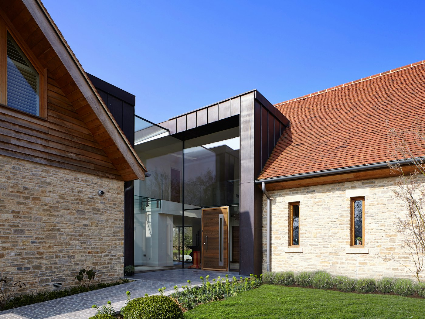 The glass of this facade dominates the entrance way but the fumed oak front door is the standout element bringing the variety of mixed building materials together 