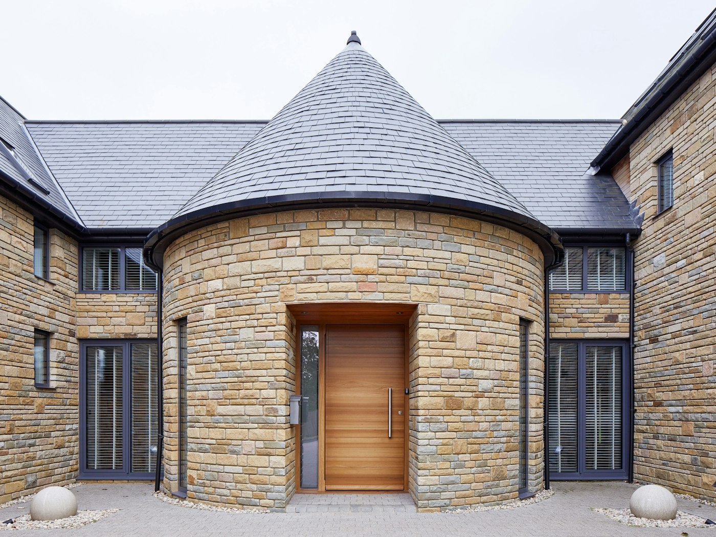 The iroko front door contrasts against the lighter stone in this house