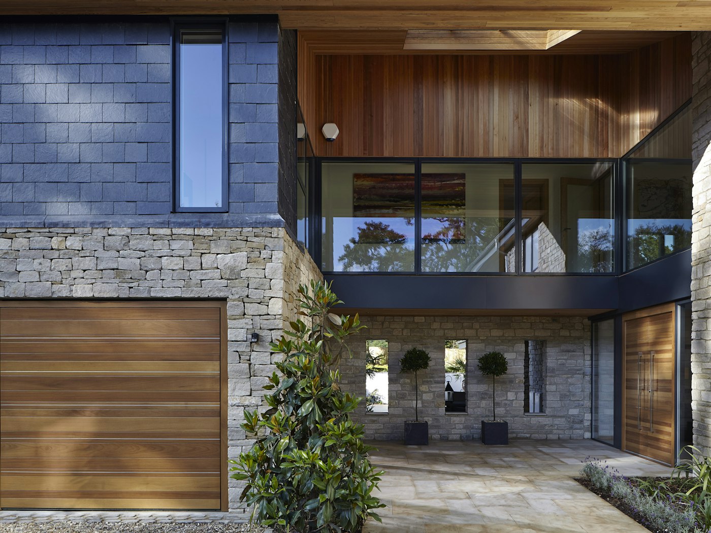 This house features mixed materials but the hardwood front door still works and matches the garage doors and wood cladding