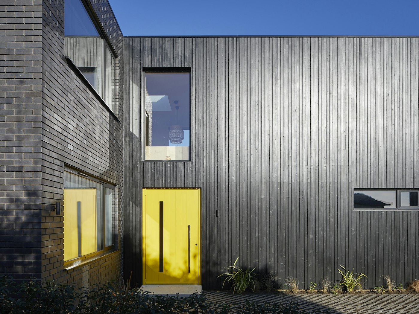 here a striking yellow door really makes a statement against the black cladding