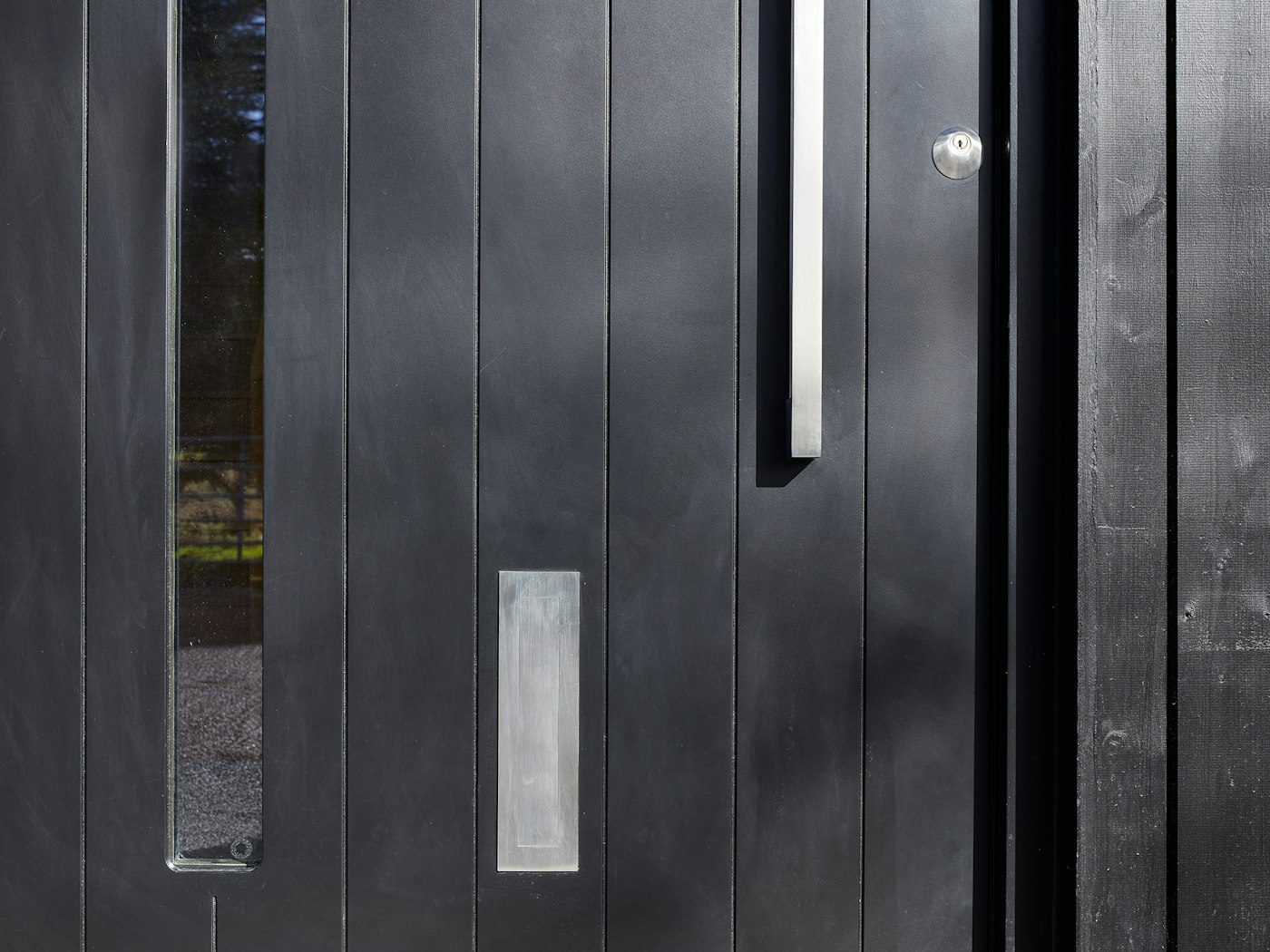 This black door design blends seamlessly into the vertical black cladding 