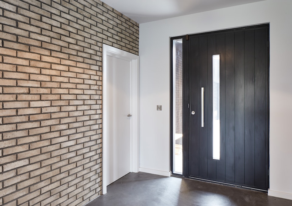 The brick wall & bright white paint nicely highlights the contemporary black door in this hallway