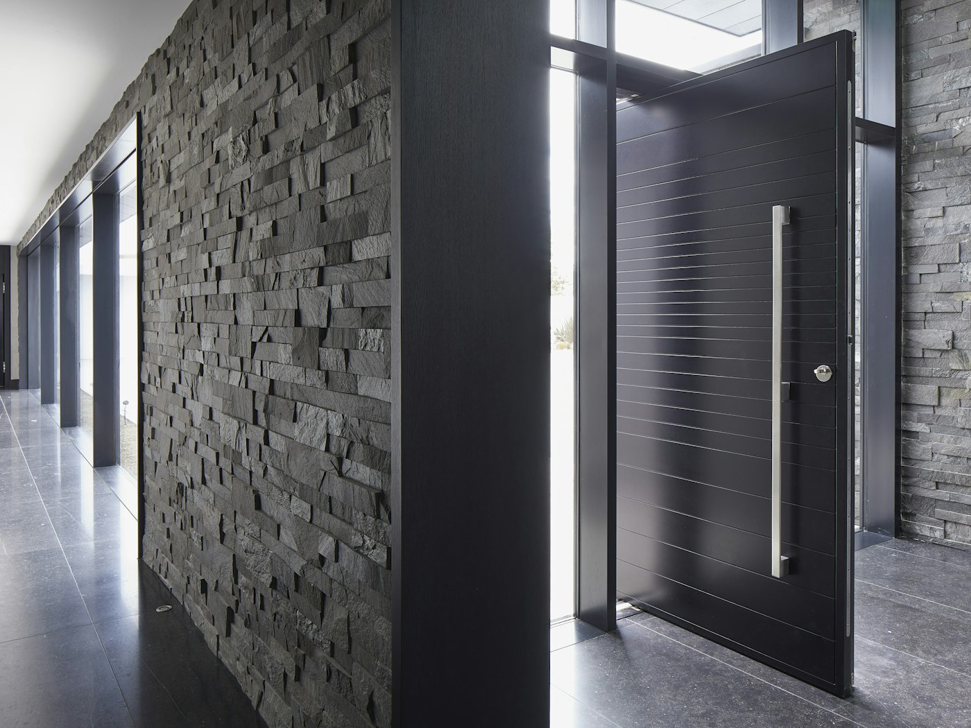 This Neo pivot doorset sits well with the dark tiled floor and the dark grey stone cladding