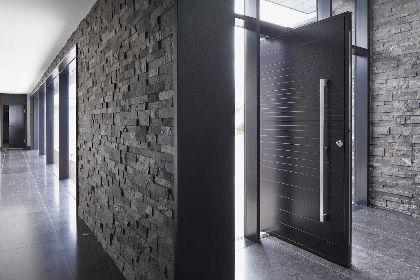 This Neo pivot doorset sits well with the dark tiled floor and the dark grey stone cladding