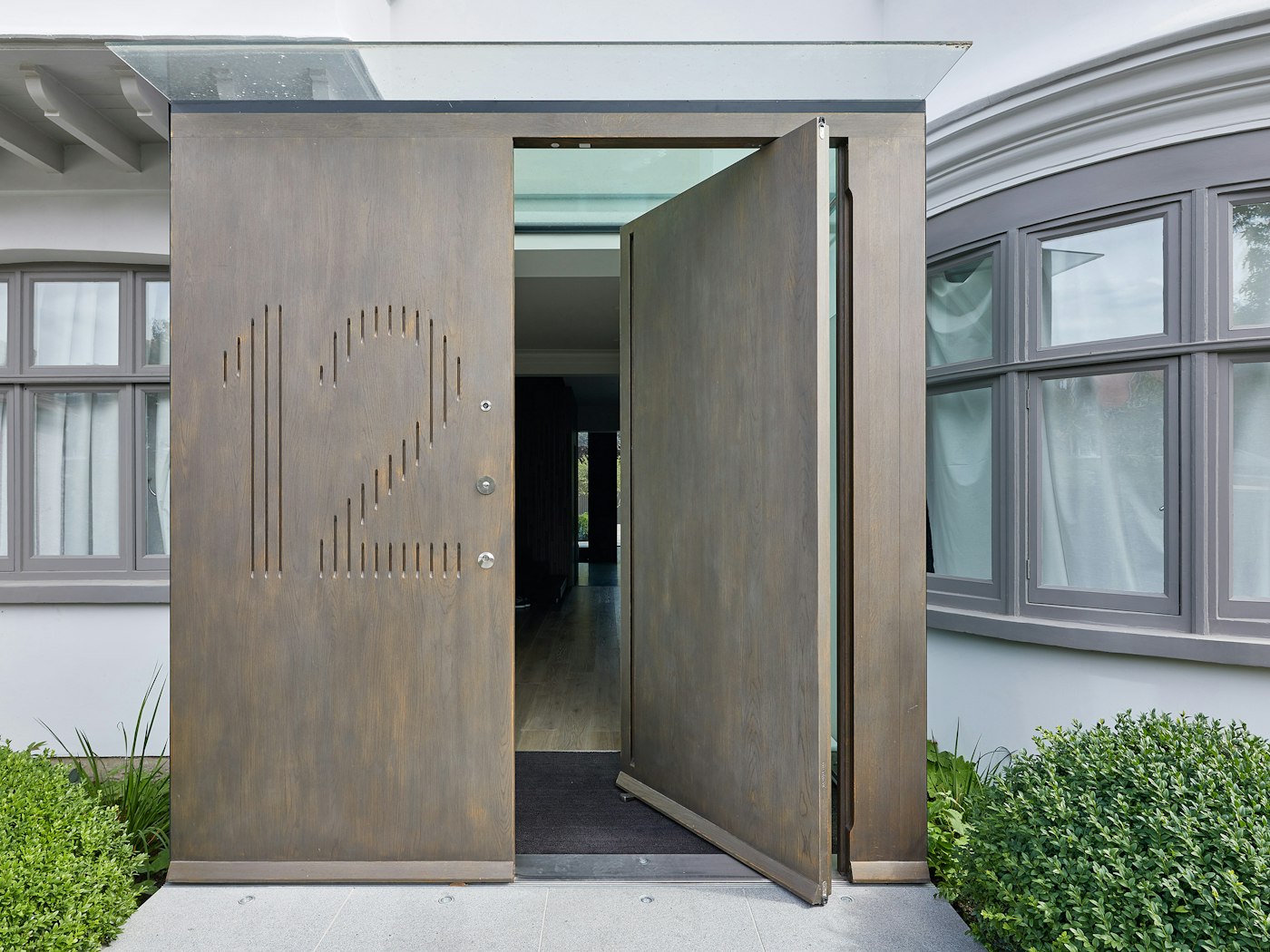 Raw E80 pivot door set with matching boarded panel with number engraving in European stained Onyx metallic finish 