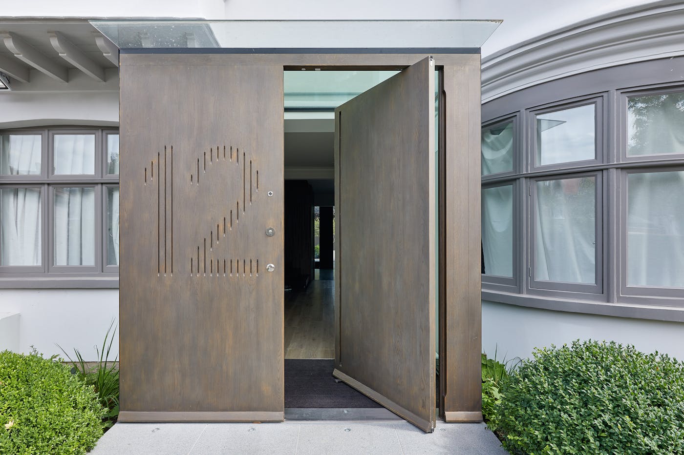 Raw E80 pivot door set with matching boarded panel with number engraving in European stained Onyx metallic finish 
