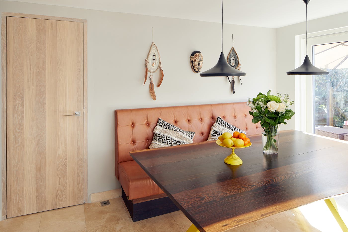 The dining area maintains the flow of more natural tones, punctuated by key splashes of colour like the fruit bowl & yellow legs on the table