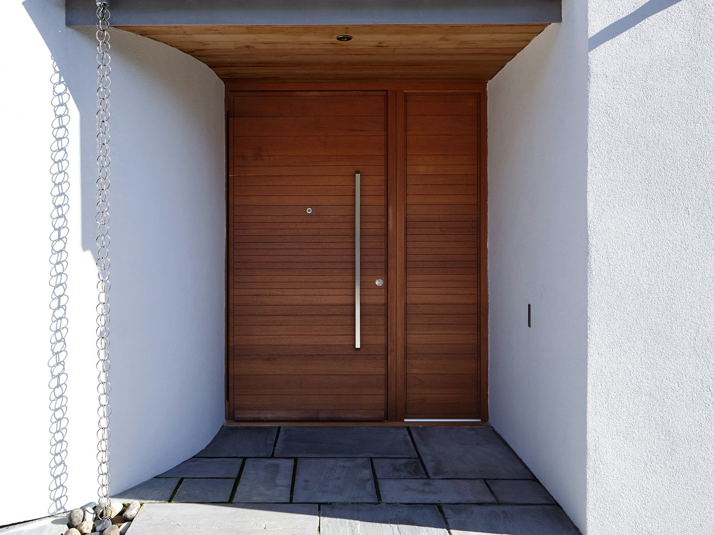 This iroko front door features a matching wood side panel to aid the perception of a wider opening