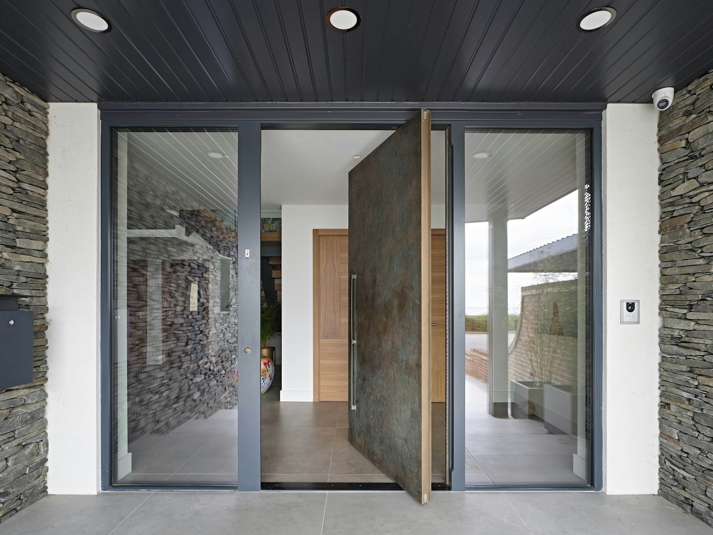 The pivot door opening is flanked by sidelights for a modern entrance