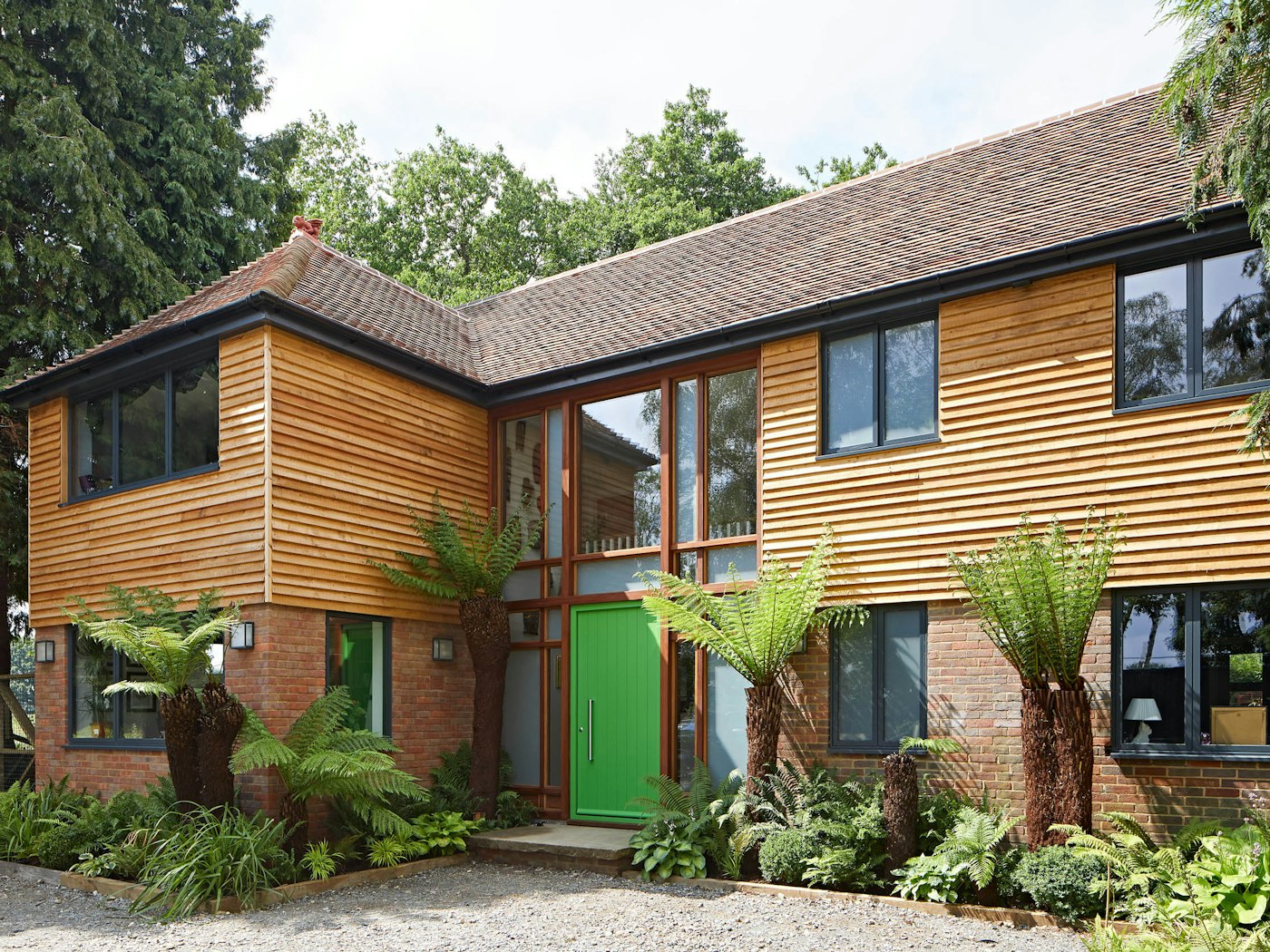 With more neutral cladding and brick tones, this bold green door adds a touch of the tropical to this beautiful property