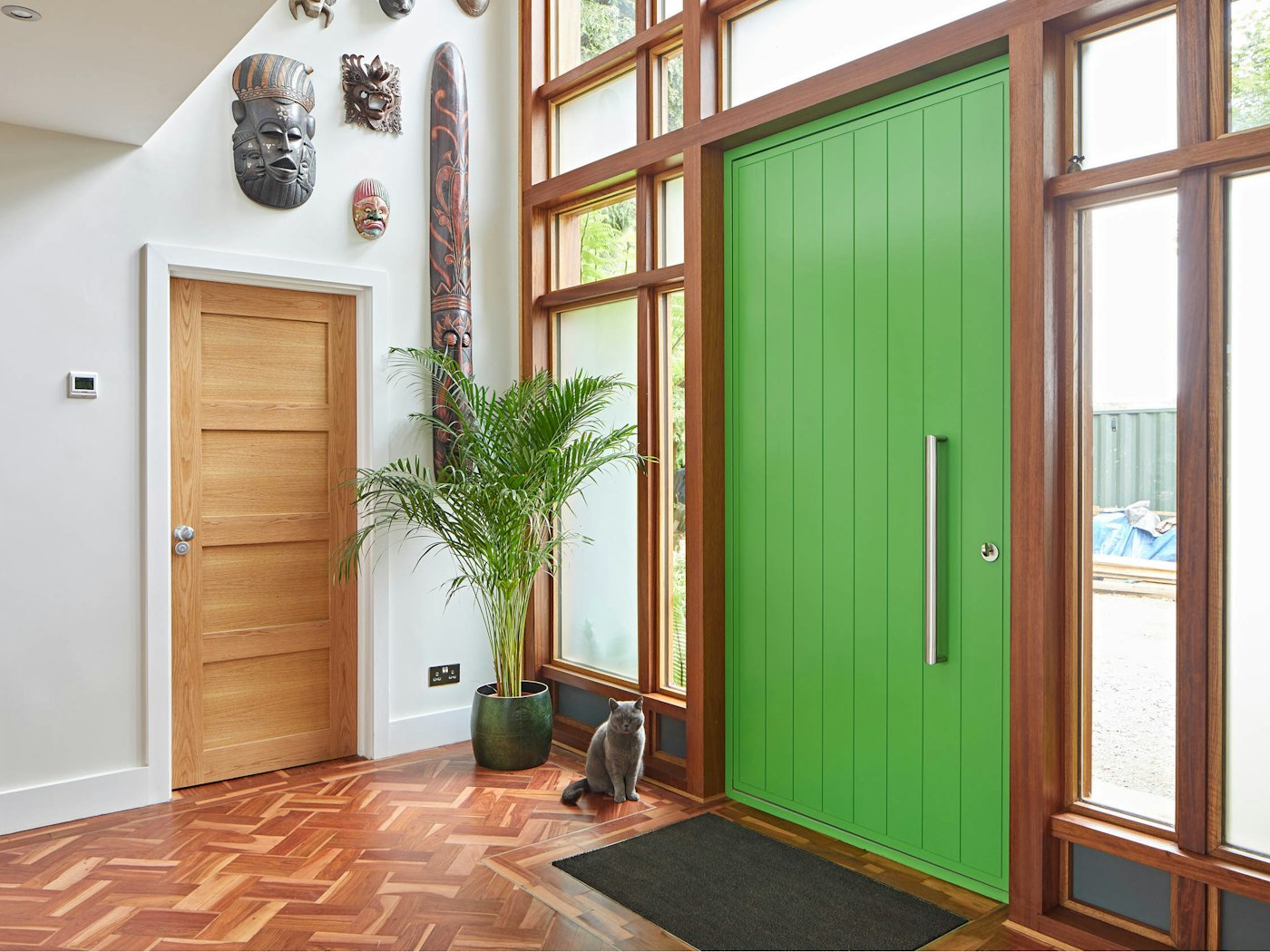 Internally, warm parquet flooring works well with the aluminium curtain frame and nicely contrasts with the vivid green door 