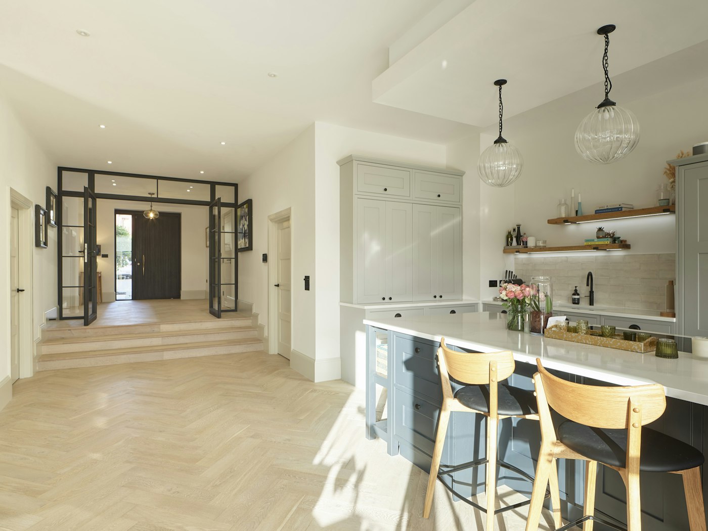 The herringbone flooring and spacious kitchen area make for an inviting space