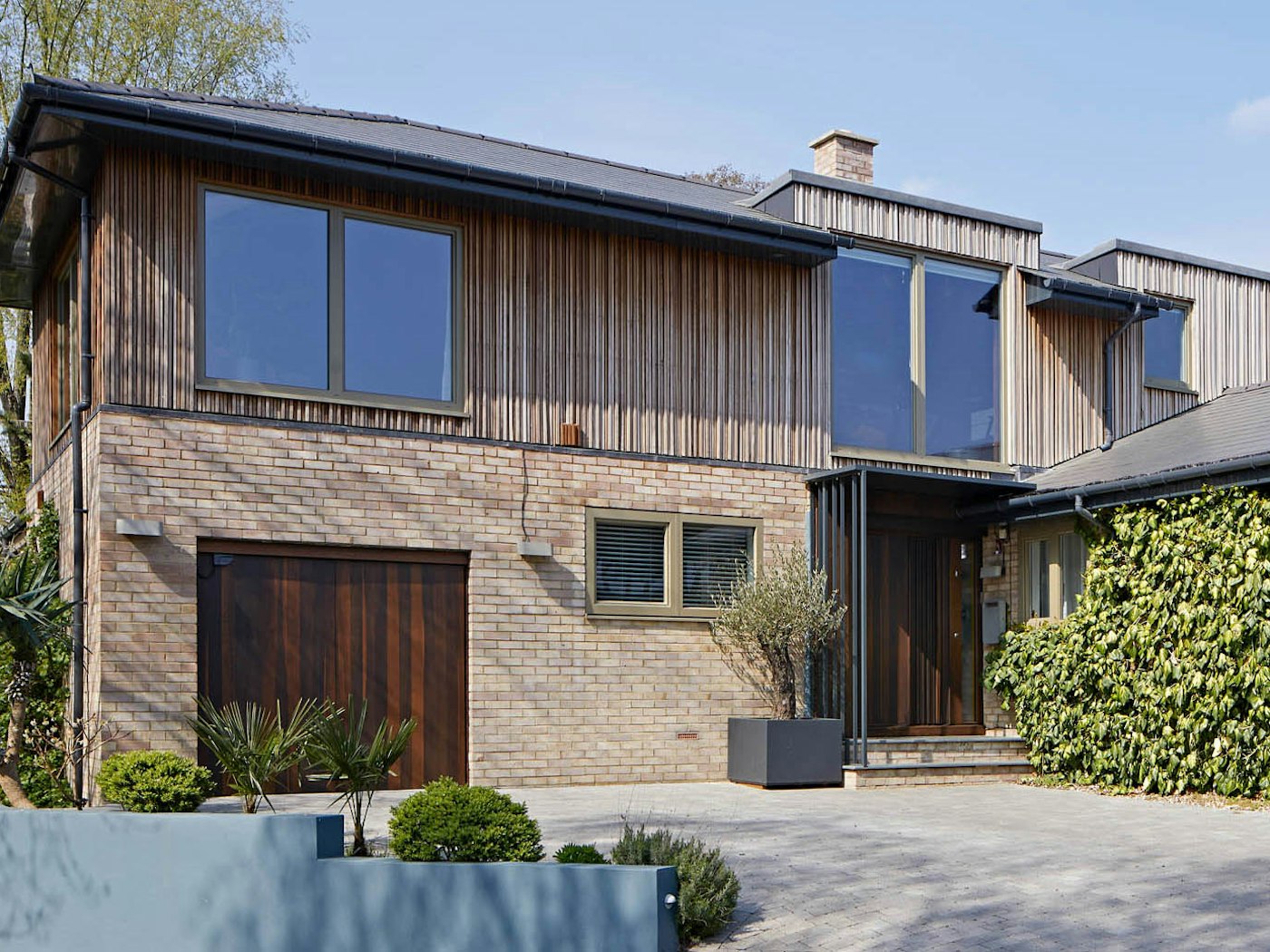 Complementing the "Bari" on this house is a "Raw" bifold garage door in the same fumed oak wood. Working together flawlessly with the exterior cladding & brickwork