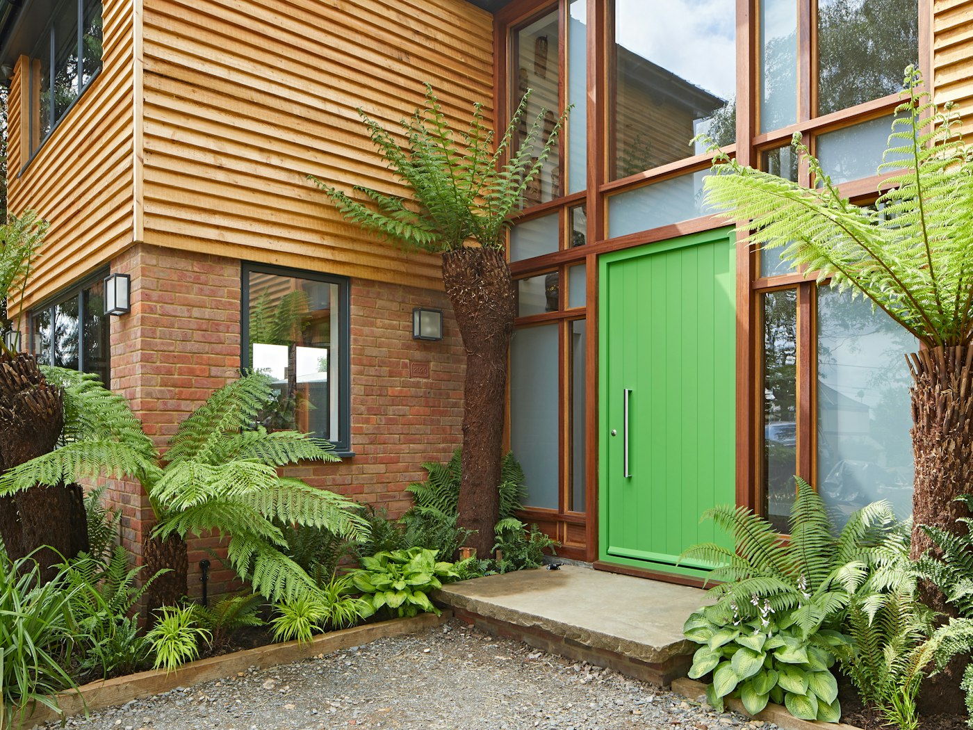 This vibrant green Porto door (painted RAL 6018) strikes a glorious note of the tropical against timber cladding and red brick 