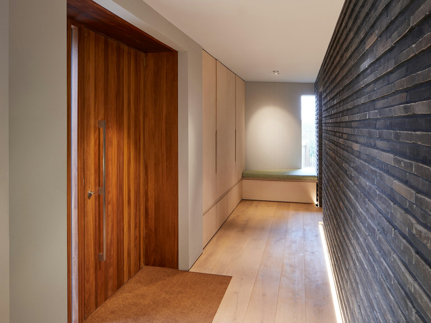 The Iroko door sits opposite a brick wall with similar raised elements works perfectly together