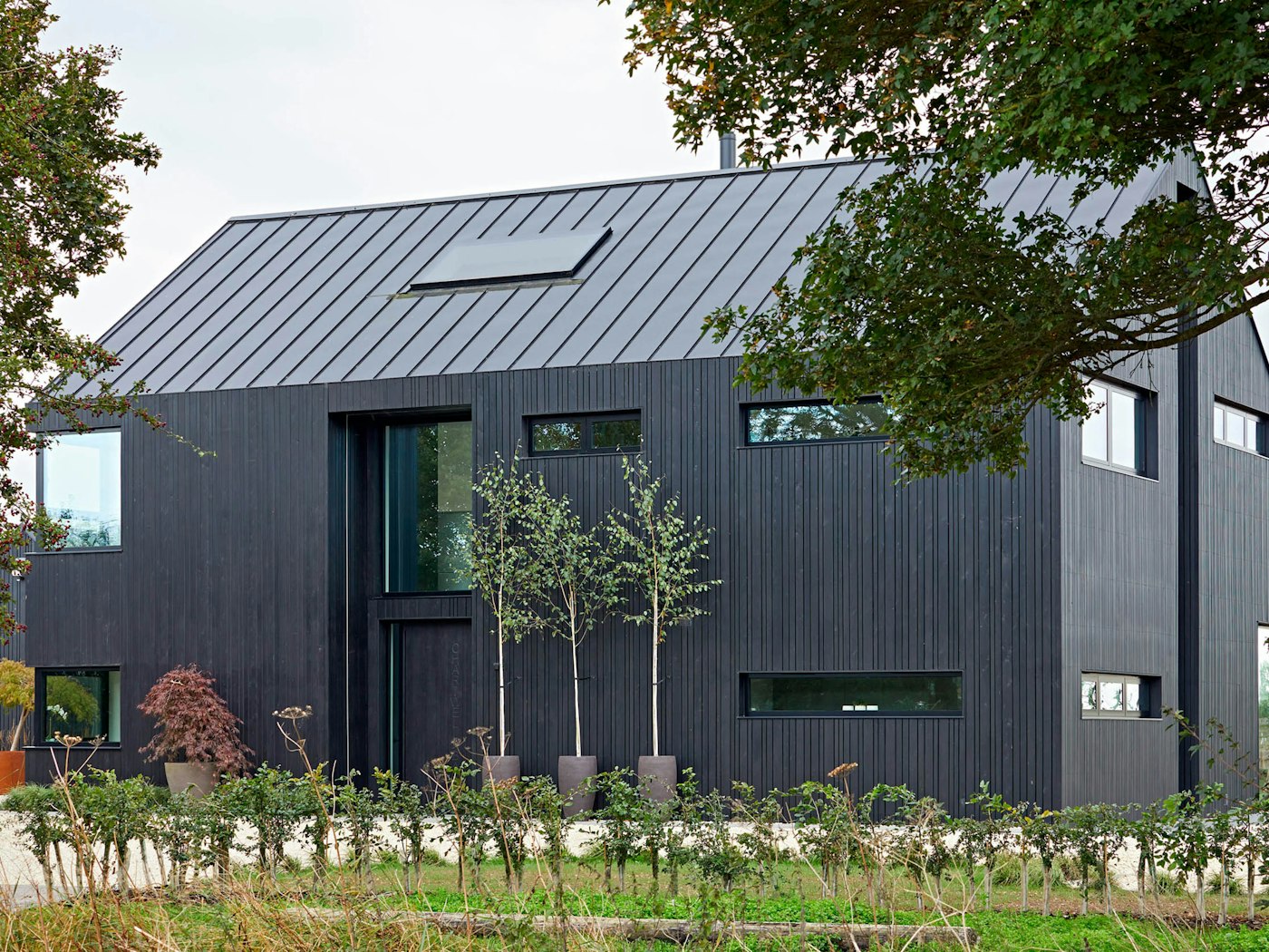 This modern, barn self-build has a sleek exterior aesthetic with the front door fitting in neatly with the black cladding